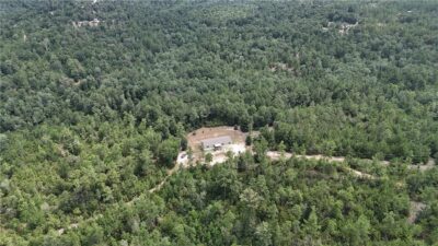 Aerial view of acreage property in the middle of wooded area